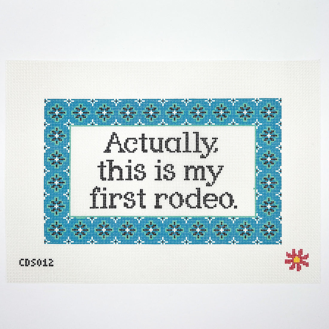 Needlepoint canvas with text on fabric with blue border and red flower, featuring the phrase &