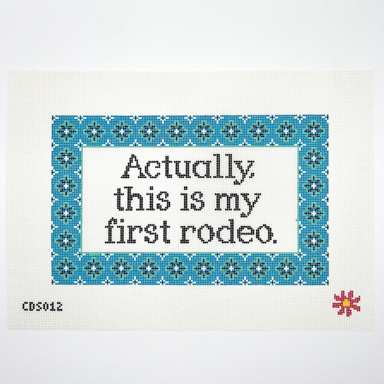 Needlepoint canvas with text on fabric with blue border and red flower, featuring the phrase &